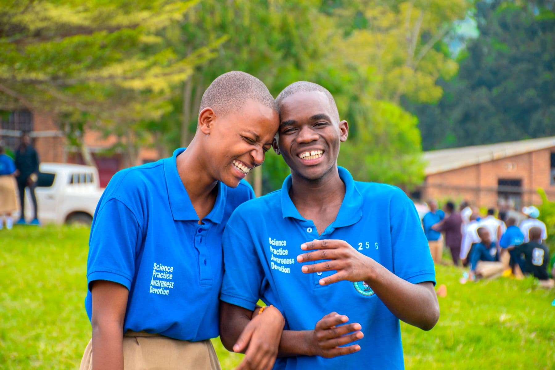 Two students laughing together outdoors in Kenya.