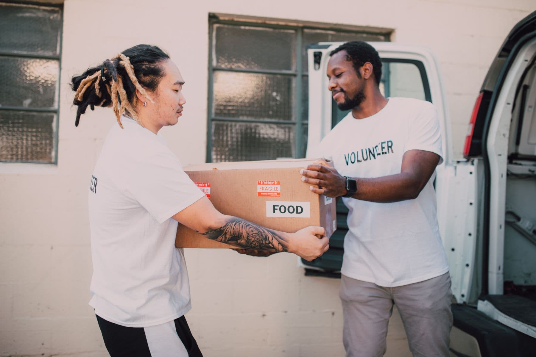 Two volunteers handing over a food parcel with care and eye contact.